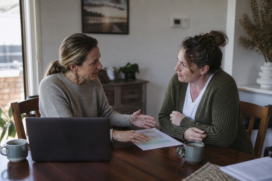 Two people discussing a support plan together at a dining table